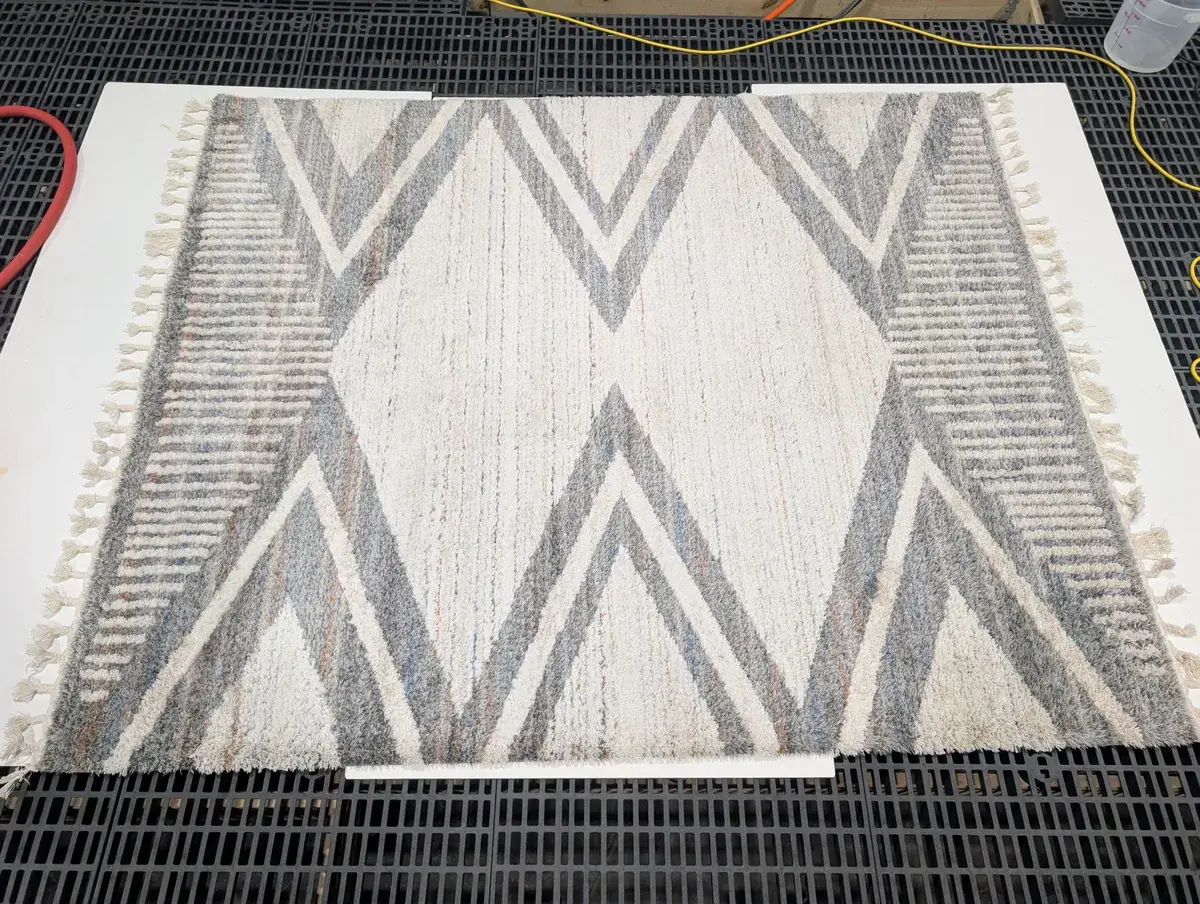 A gray and cream synthetic rug with a chevron pattern, ready for cleaning at our Springfield, VA facility